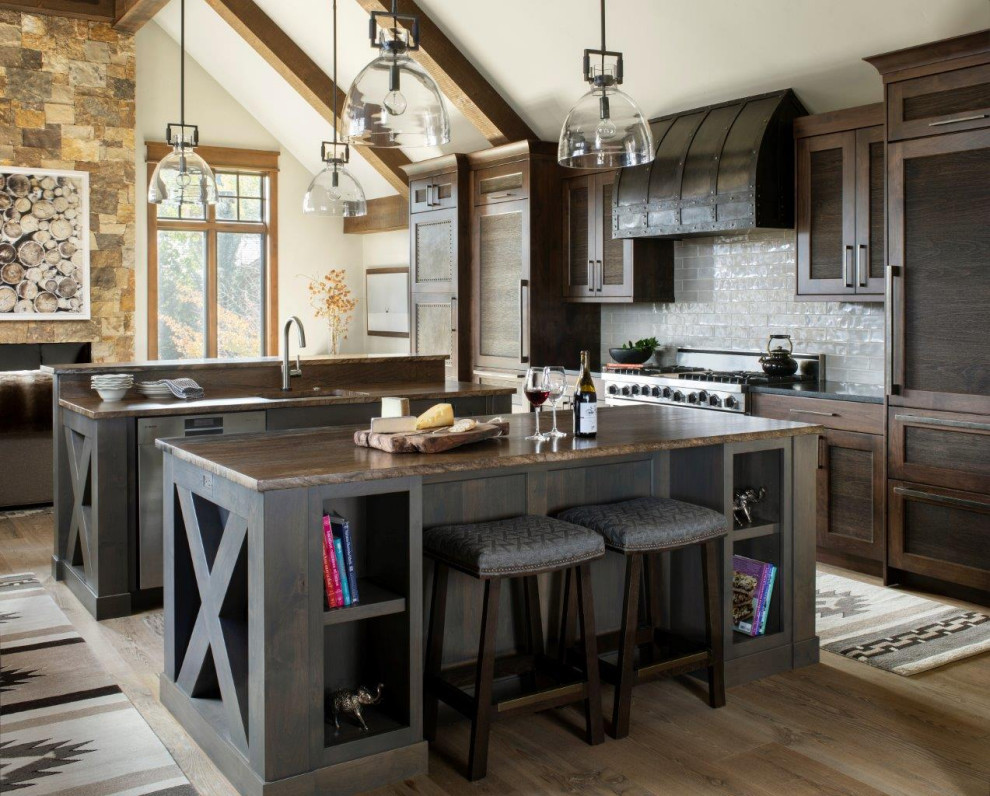 Photo of a country u-shaped kitchen in Denver with an undermount sink, shaker cabinets, dark wood cabinets, panelled appliances, medium hardwood floors, multiple islands, brown floor, brown benchtop and exposed beam.