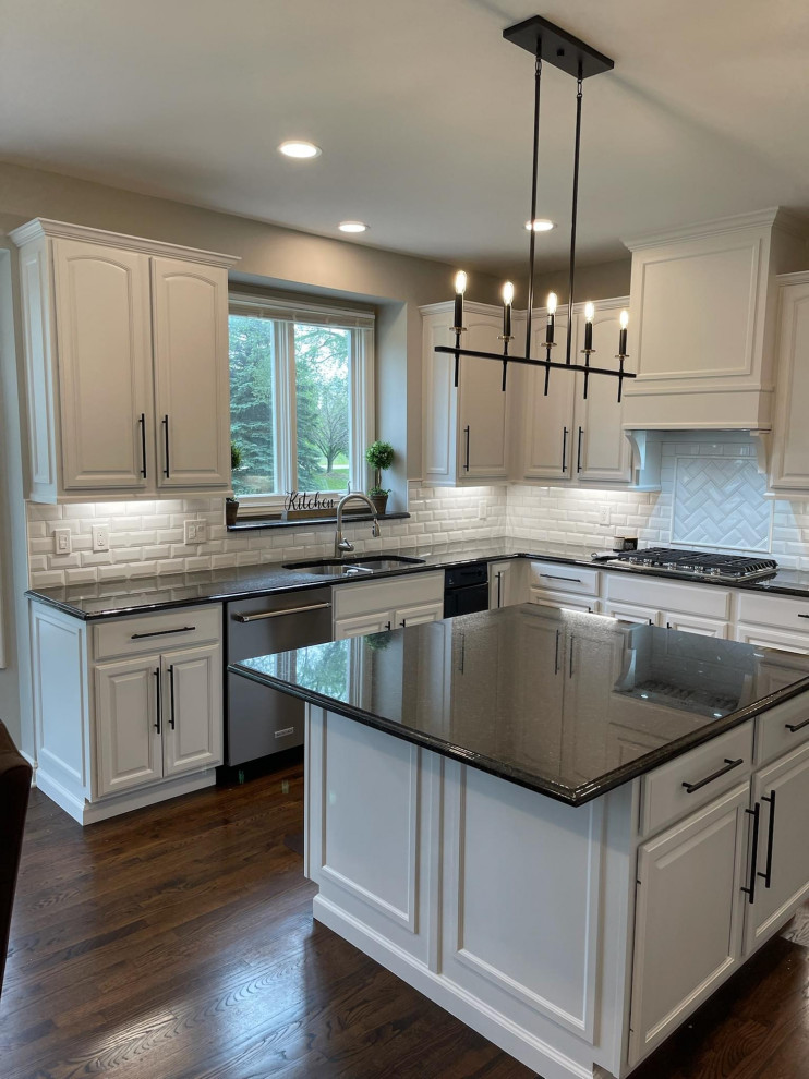 Mittelgroße Moderne Küche mit weißen Schränken, Granit-Arbeitsplatte, Küchenrückwand in Weiß, Rückwand aus Backstein, Kücheninsel und schwarzer Arbeitsplatte in Detroit