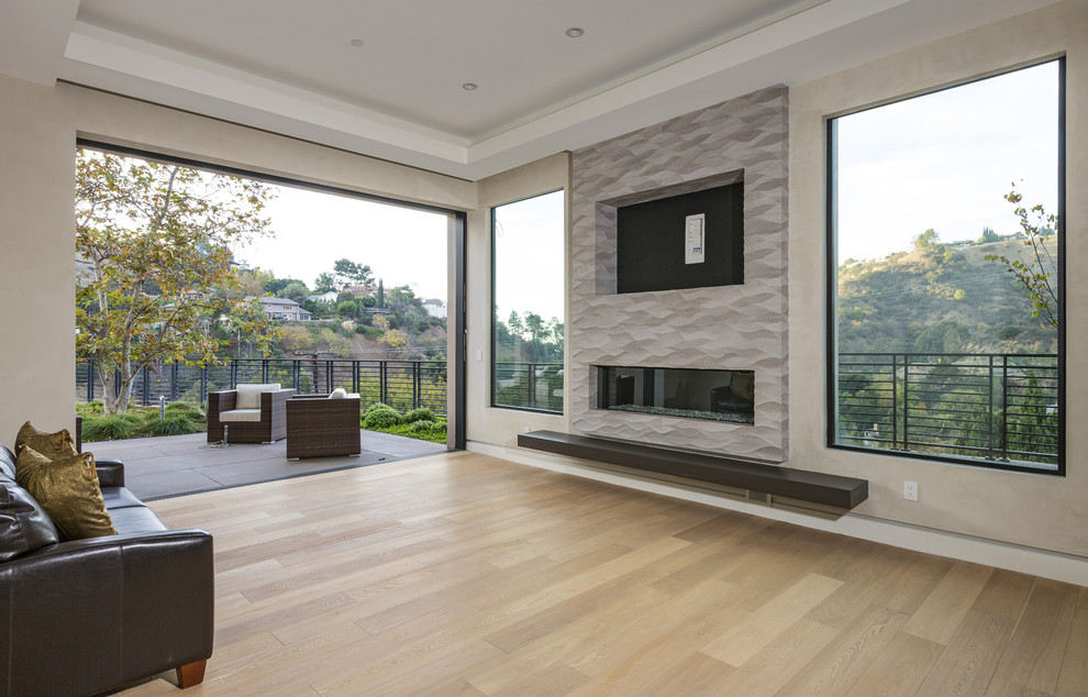 Expansive modern open concept living room in Los Angeles with beige walls, light hardwood floors, a ribbon fireplace, a plaster fireplace surround, a built-in media wall and brown floor.
