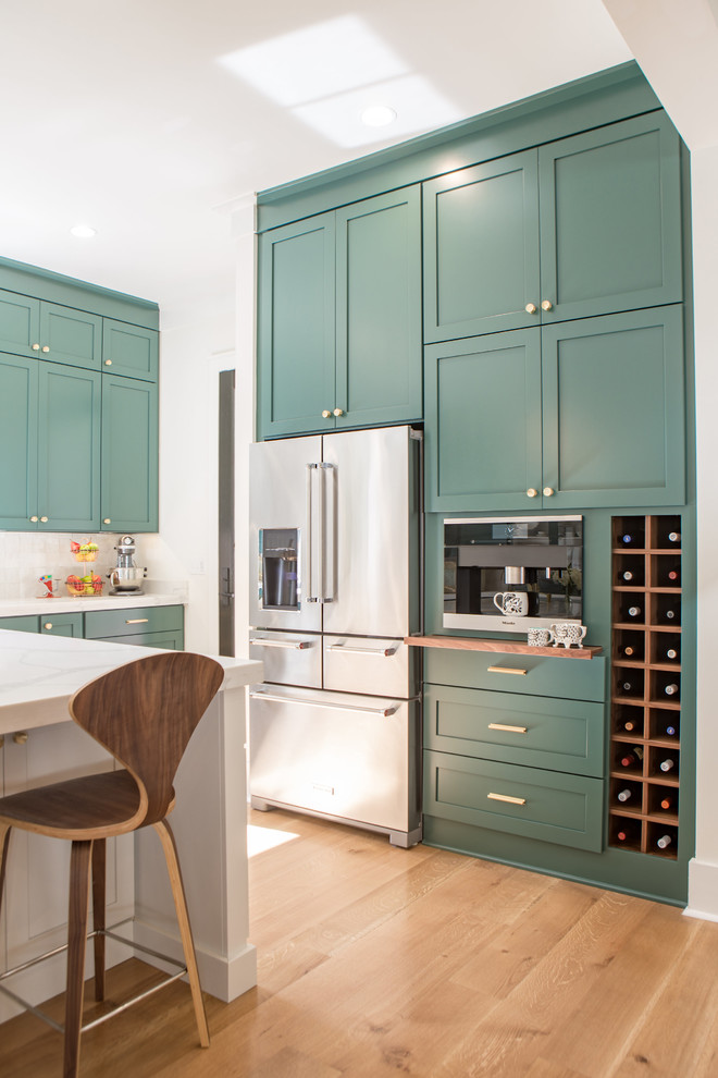 Open concept kitchen - large transitional u-shaped light wood floor open concept kitchen idea with shaker cabinets, green cabinets, quartz countertops, white backsplash, stainless steel appliances and an island
