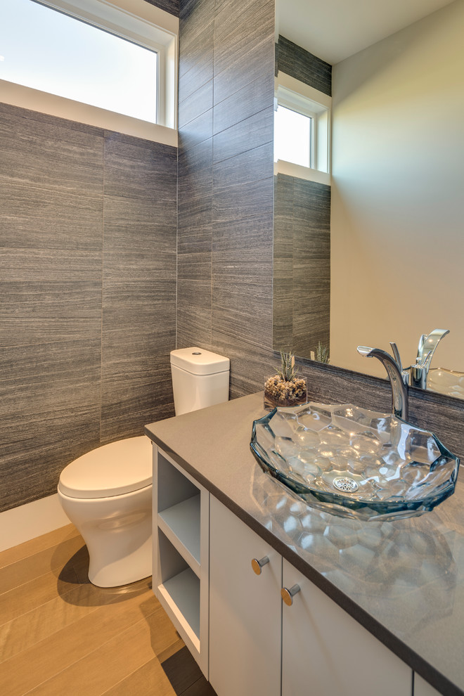 Design ideas for a small transitional powder room in Vancouver with flat-panel cabinets, white cabinets, quartzite benchtops, a one-piece toilet, gray tile, ceramic tile, a vessel sink, light hardwood floors and grey benchtops.