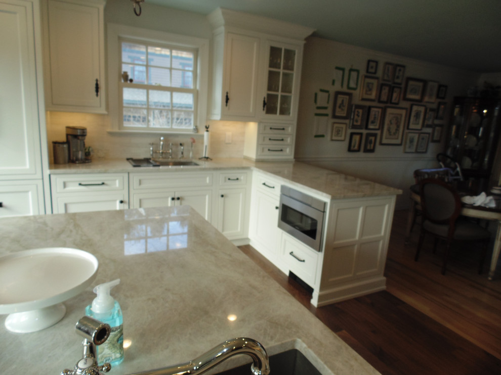 Inspiration for a large transitional u-shaped medium tone wood floor and brown floor eat-in kitchen remodel with an undermount sink, recessed-panel cabinets, white cabinets, quartzite countertops, beige backsplash, subway tile backsplash, stainless steel appliances, an island and beige countertops