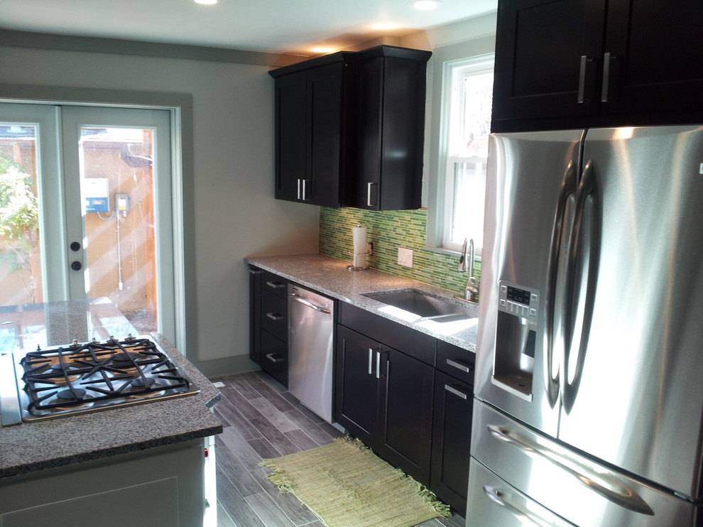 Photo of a contemporary separate kitchen in Denver with an undermount sink, shaker cabinets, black cabinets, quartzite benchtops, green splashback and stainless steel appliances.