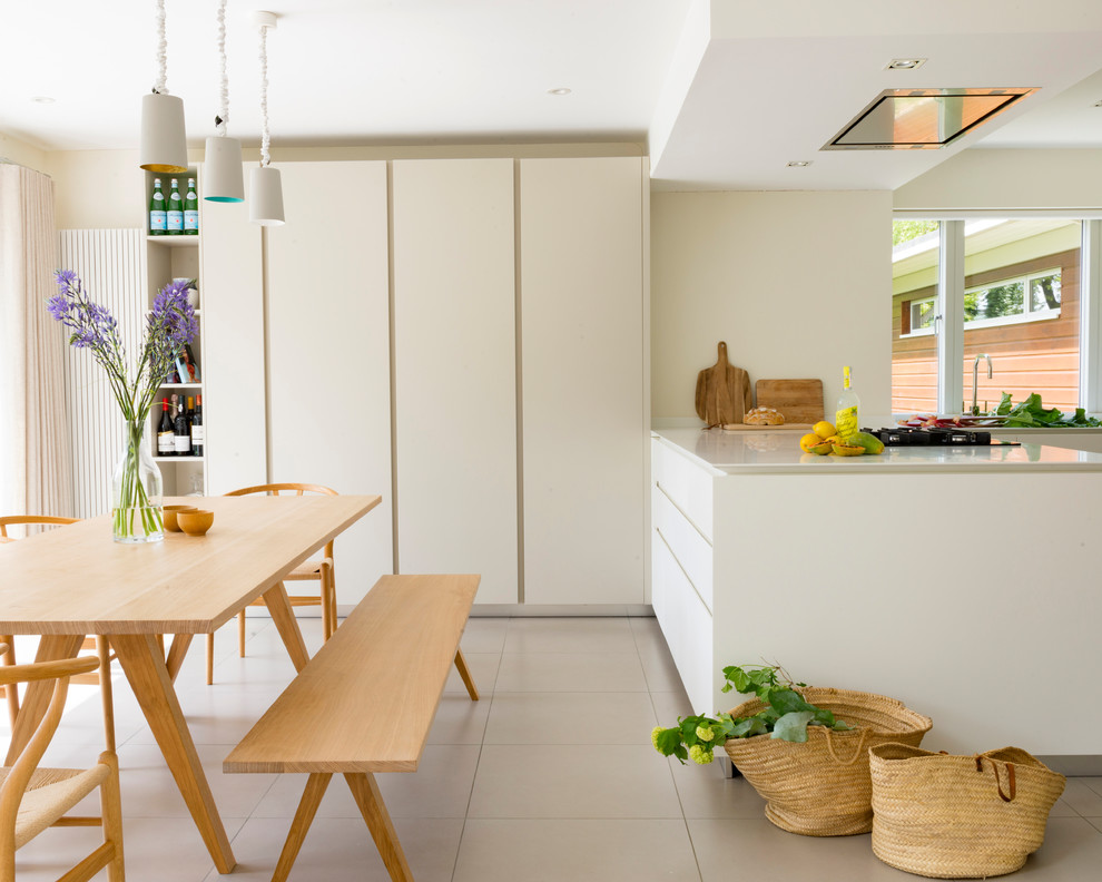 Design ideas for a mid-sized contemporary kitchen in Sussex with flat-panel cabinets, white cabinets, quartzite benchtops, white splashback, glass sheet splashback, with island and white benchtop.
