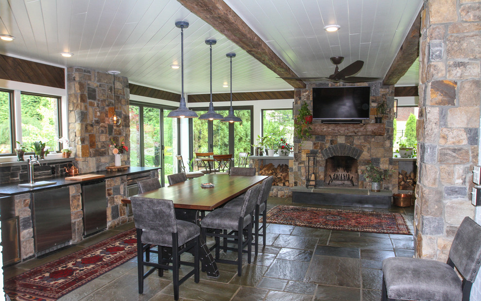 This is an example of a large arts and crafts sunroom in Other with limestone floors, a standard fireplace, a stone fireplace surround and multi-coloured floor.