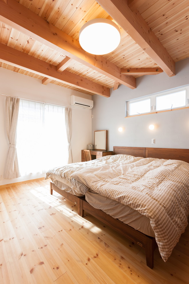 Immagine di una camera da letto etnica con pareti bianche, pavimento in legno massello medio e pavimento marrone