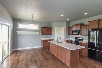 Inspiration for a mid-sized transitional l-shaped medium tone wood floor eat-in kitchen remodel with an undermount sink, recessed-panel cabinets, medium tone wood cabinets, quartz countertops, black appliances and an island