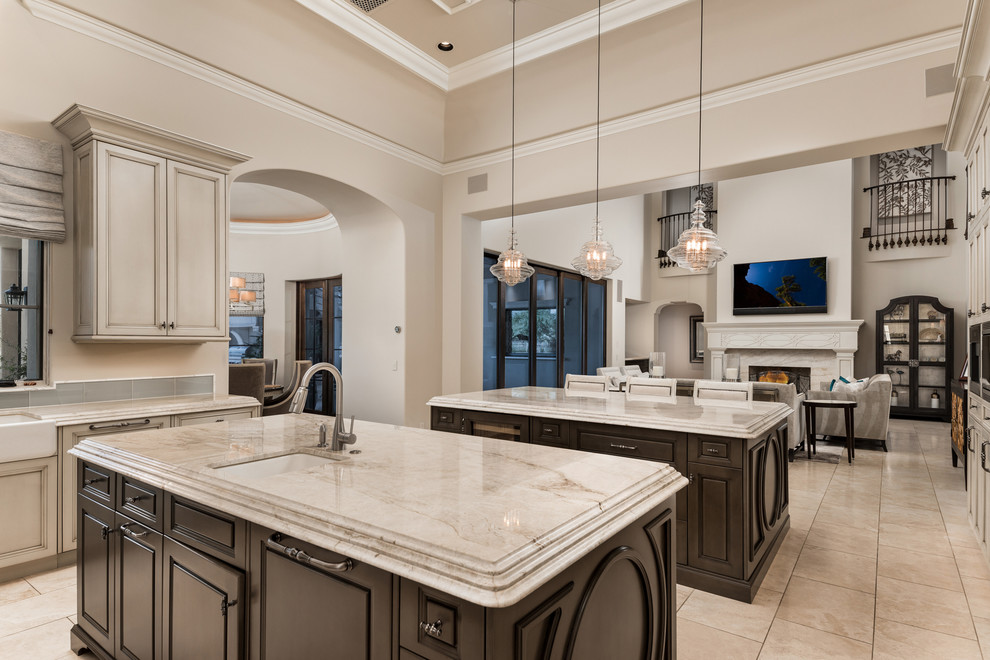 This is an example of an expansive mediterranean u-shaped open plan kitchen in Phoenix with an undermount sink, recessed-panel cabinets, quartzite benchtops, multi-coloured splashback, porcelain splashback, stainless steel appliances, porcelain floors, multiple islands, multi-coloured floor, beige benchtop and dark wood cabinets.