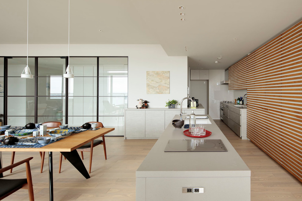 Inredning av ett modernt stort grå grått kök, med en undermonterad diskho, luckor med profilerade fronter, grå skåp, bänkskiva i kvarts, vitt stänkskydd, stänkskydd i glaskakel, rostfria vitvaror, ljust trägolv, en köksö och beiget golv