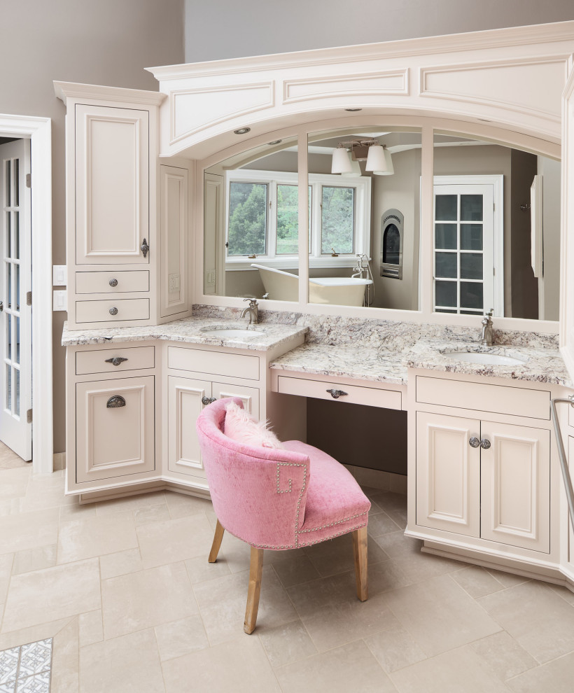 This is an example of a large traditional master bathroom in Other with beaded inset cabinets, beige cabinets, a claw-foot tub, a corner shower, a one-piece toilet, beige tile, porcelain tile, brown walls, porcelain floors, an undermount sink, granite benchtops, beige floor, a hinged shower door, beige benchtops, an enclosed toilet, a double vanity, a built-in vanity and vaulted.