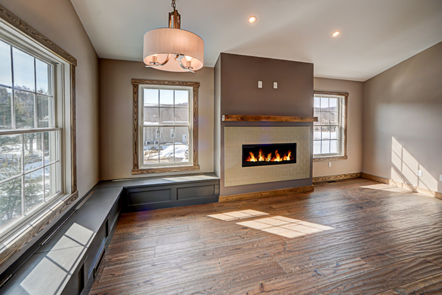 Photo of a country open plan dining in New York with beige walls, medium hardwood floors, a standard fireplace and a tile fireplace surround.
