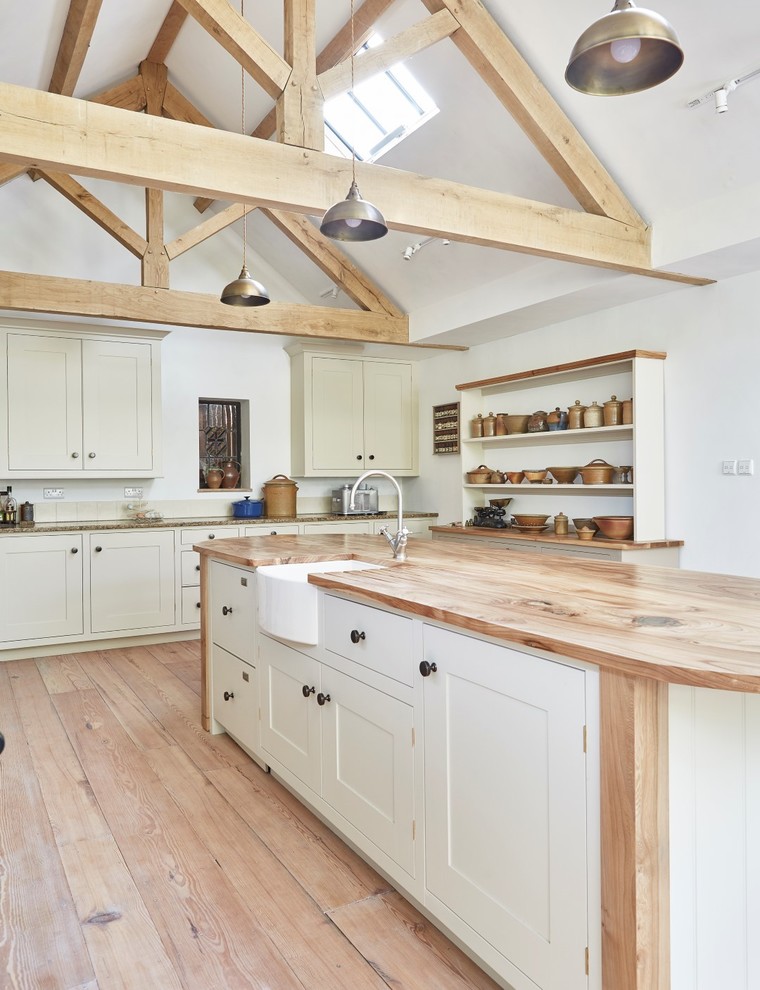 Mid-sized traditional galley open plan kitchen in Devon with a farmhouse sink, shaker cabinets, beige cabinets, wood benchtops, beige splashback, ceramic splashback, stainless steel appliances, medium hardwood floors, with island, brown floor and brown benchtop.
