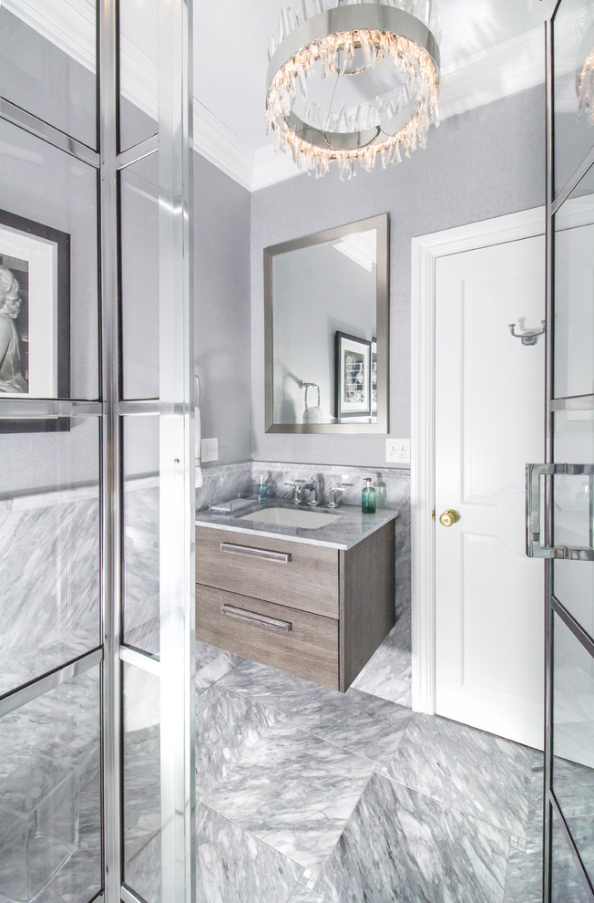 Photo of a mid-sized transitional 3/4 bathroom in New York with flat-panel cabinets, dark wood cabinets, a corner shower, a one-piece toilet, gray tile, marble, grey walls, marble floors, an undermount sink, marble benchtops, grey floor and a hinged shower door.