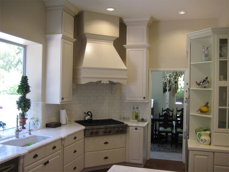 Mid-sized transitional u-shaped dark wood floor and brown floor enclosed kitchen photo in Orange County with an undermount sink, raised-panel cabinets, white cabinets, solid surface countertops, white backsplash, subway tile backsplash, stainless steel appliances and an island