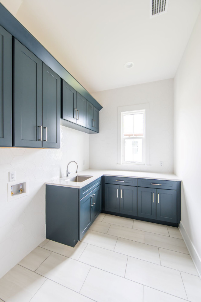 Design ideas for a large transitional l-shaped dedicated laundry room in Jacksonville with an undermount sink, shaker cabinets, blue cabinets, quartz benchtops, white splashback, porcelain splashback, white walls, light hardwood floors, a side-by-side washer and dryer, brown floor and white benchtop.