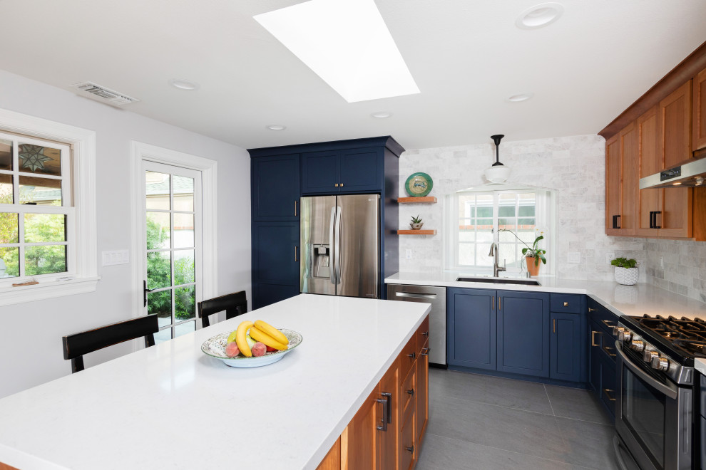 Inspiration for a mid-sized transitional l-shaped ceramic tile and gray floor enclosed kitchen remodel in Orange County with an undermount sink, shaker cabinets, blue cabinets, quartz countertops, gray backsplash, marble backsplash, stainless steel appliances, an island and white countertops