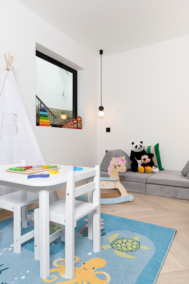 Ejemplo de habitación de bebé neutra contemporánea de tamaño medio con paredes blancas y suelo de madera clara