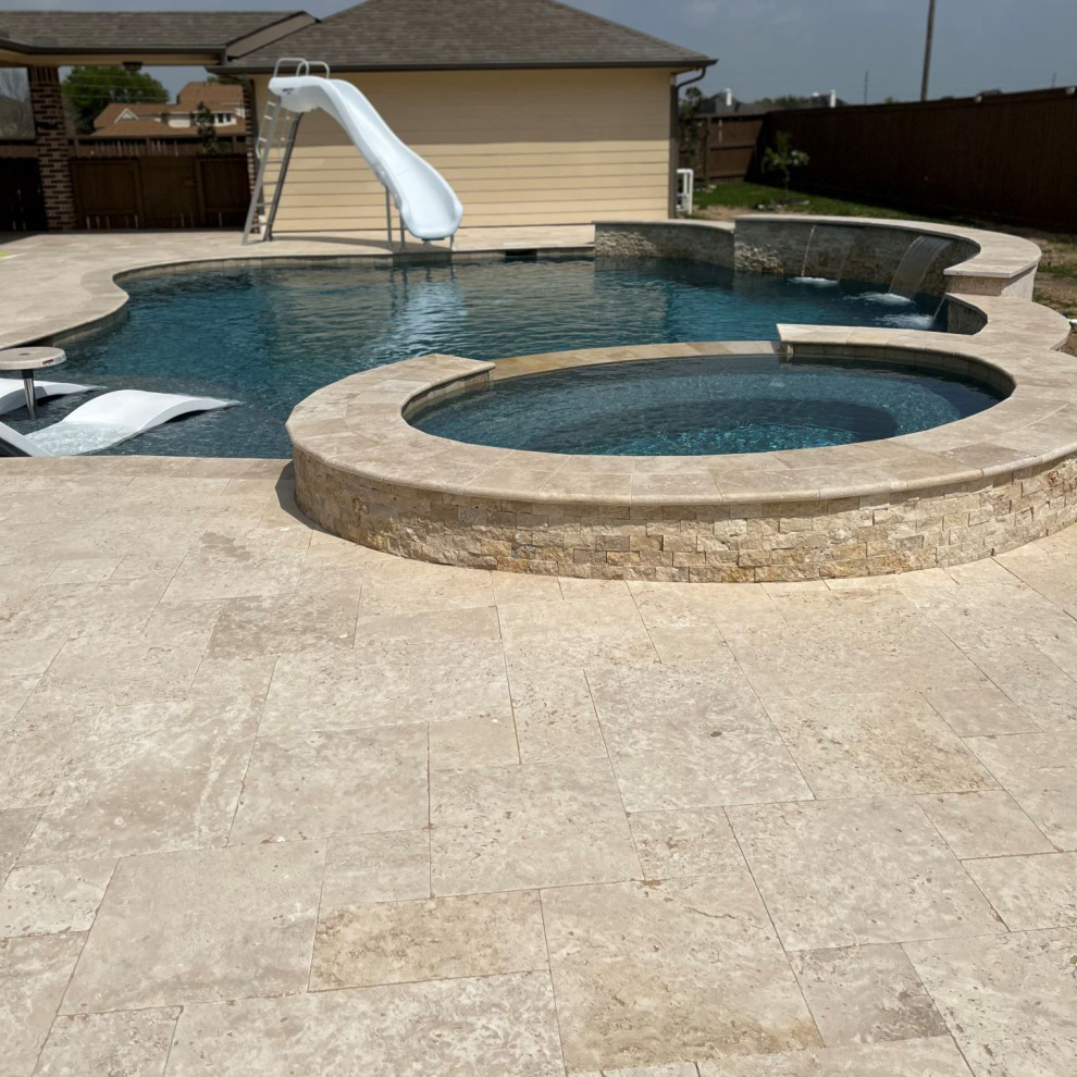 Großer Pool hinter dem Haus in individueller Form mit Wasserrutsche und Natursteinplatten in Houston