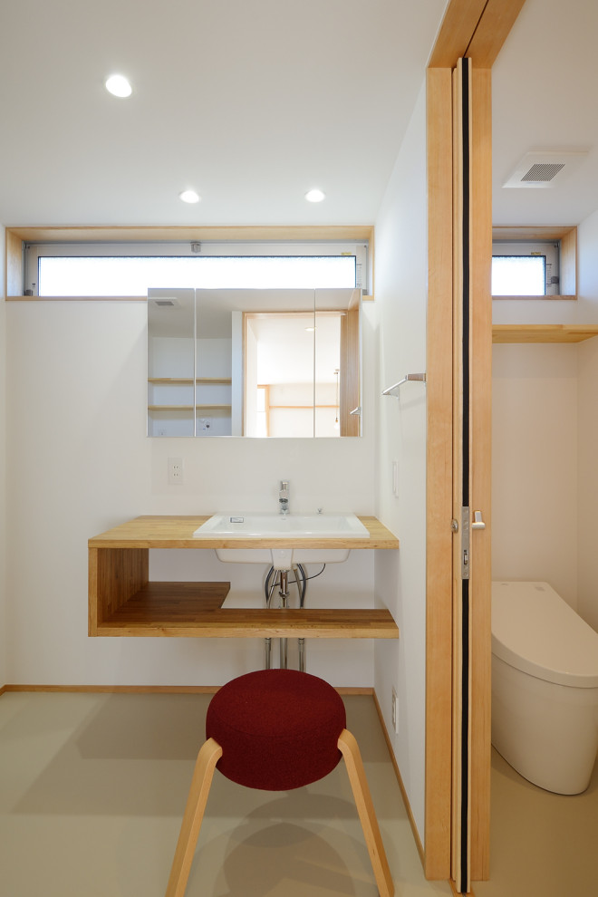 Exemple d'un WC et toilettes scandinave en bois brun de taille moyenne avec un placard sans porte, WC à poser, un mur blanc, un sol en vinyl, un lavabo encastré, un plan de toilette en bois, un sol beige, un plan de toilette beige, meuble-lavabo encastré, un plafond en papier peint et du papier peint.
