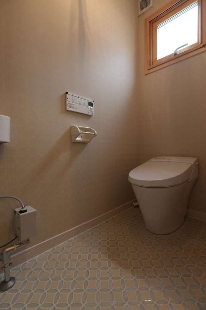 Foto på ett skandinaviskt toalett, med en toalettstol med separat cisternkåpa, flerfärgad kakel, glaskakel, beige väggar och ett väggmonterat handfat