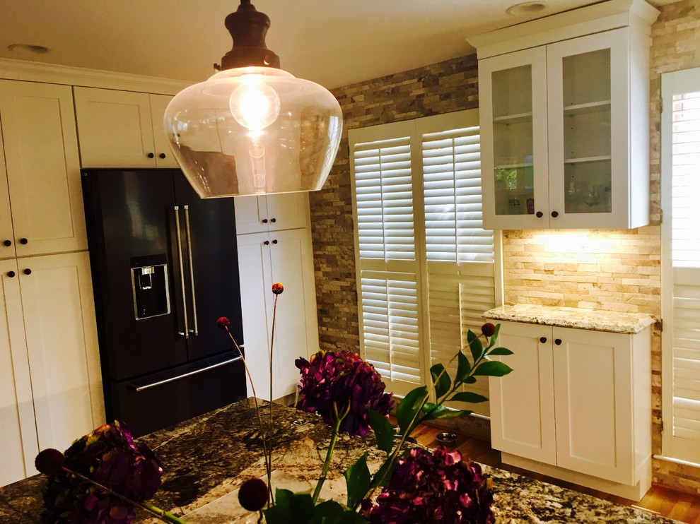 Example of a mid-sized transitional l-shaped medium tone wood floor and brown floor open concept kitchen design in DC Metro with an undermount sink, shaker cabinets, white cabinets, granite countertops, beige backsplash, stone tile backsplash, stainless steel appliances and a peninsula