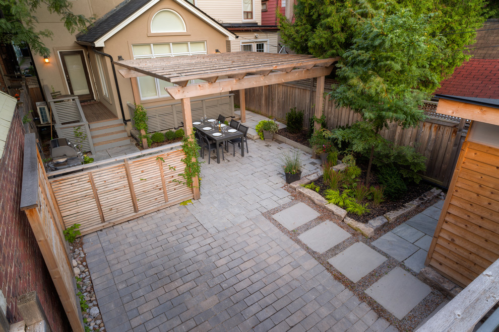 Mid-sized modern backyard patio in Toronto with concrete pavers and a pergola.