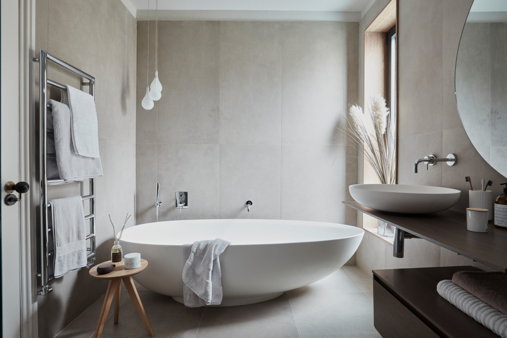 Inspiration for a large contemporary master bathroom in London with a freestanding tub, beige tile, porcelain tile, porcelain floors, a vessel sink, beige floor, brown benchtops and flat-panel cabinets.