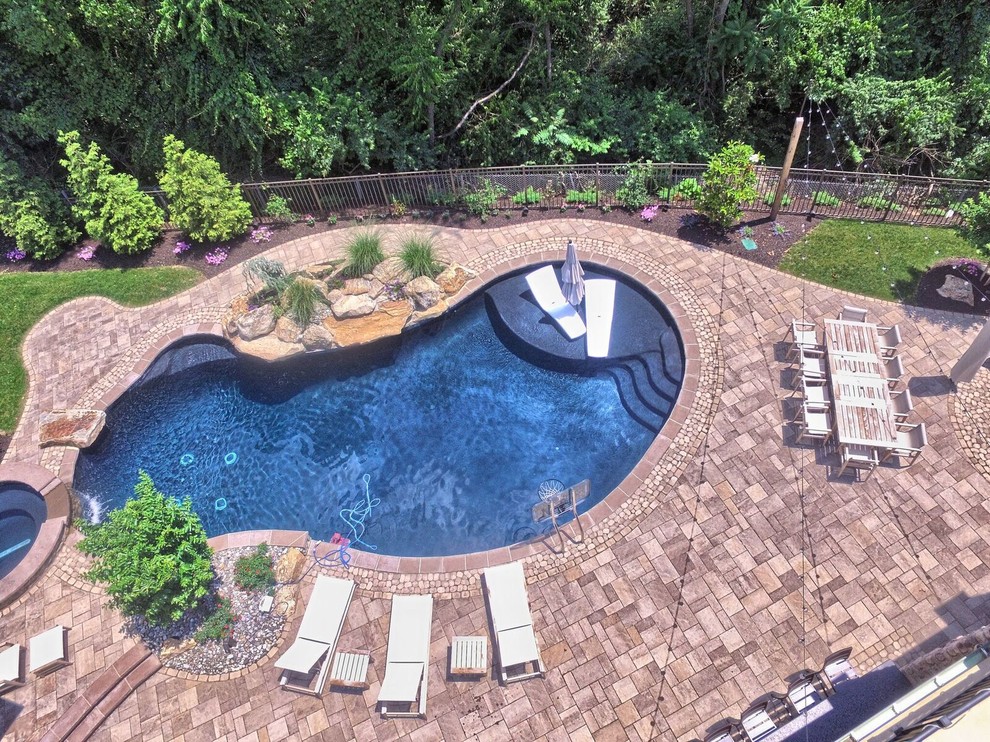 Large contemporary backyard kidney-shaped pool in Philadelphia with a hot tub and concrete pavers.