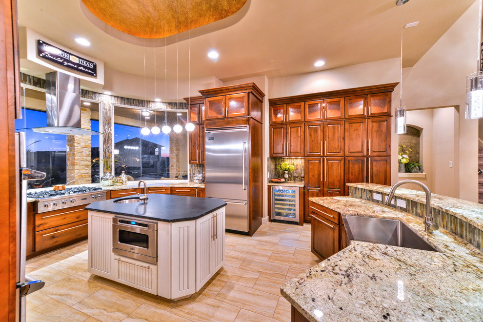 Inspiration for a transitional kitchen in Austin with an undermount sink, medium wood cabinets, granite benchtops, green splashback, stainless steel appliances, travertine floors and multiple islands.