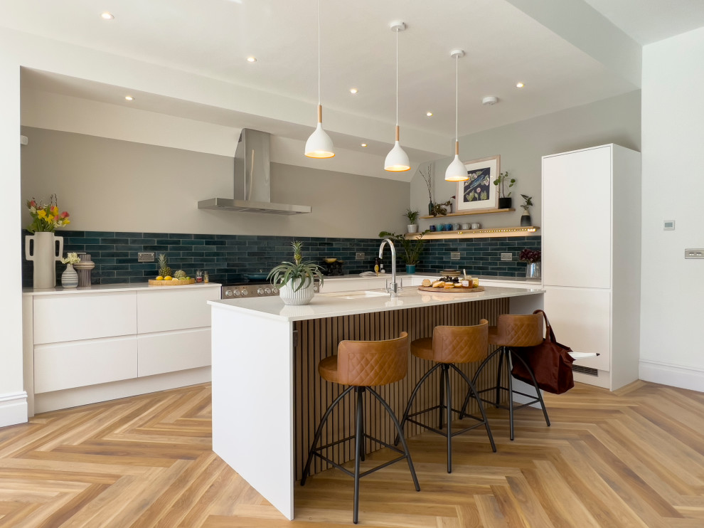 This is an example of a large contemporary l-shaped eat-in kitchen in Other with an undermount sink, flat-panel cabinets, white cabinets, blue splashback, porcelain splashback, stainless steel appliances, vinyl floors, with island and white benchtop.