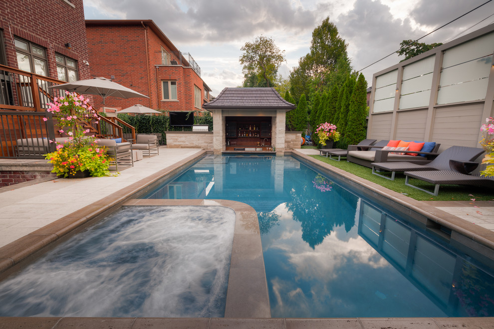 Photo of a large modern backyard rectangular pool in Other with a water feature and natural stone pavers.