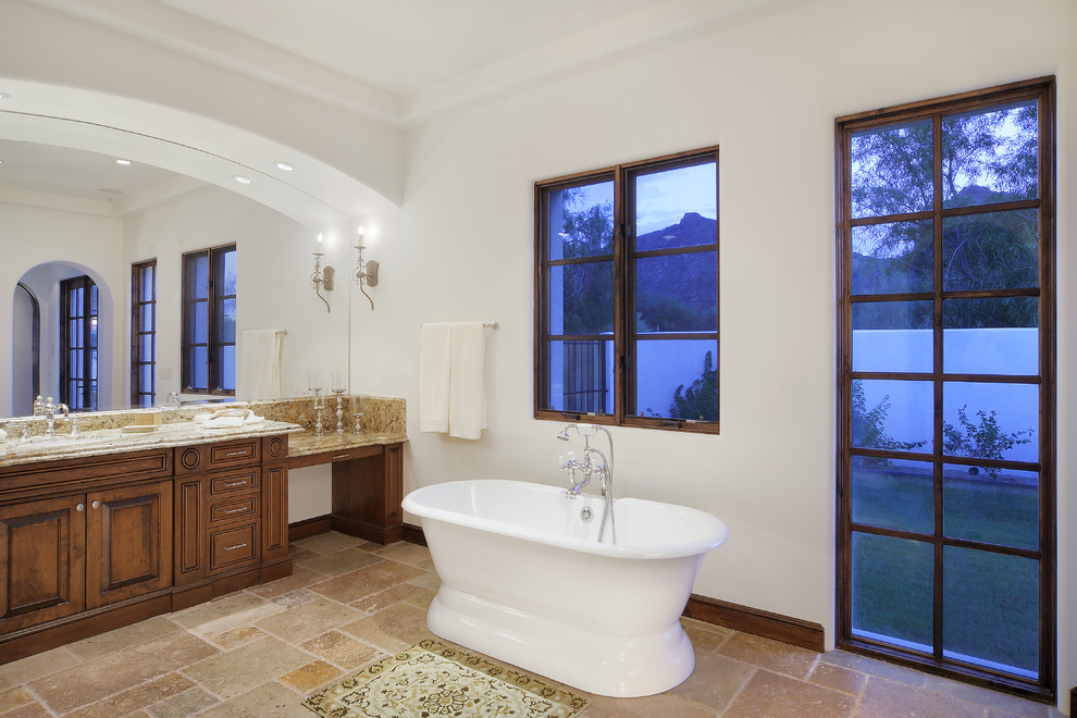 This is an example of a mediterranean bathroom in Phoenix with a freestanding tub and granite benchtops.