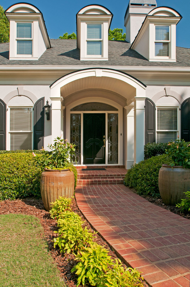 Elegant brick front porch photo in Atlanta with a roof extension