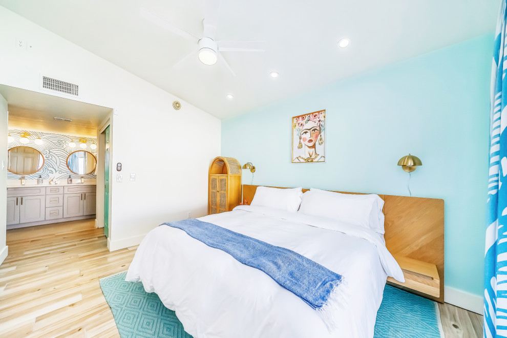 Exemple d'une grande chambre parentale tendance avec un mur bleu, un sol en contreplaqué, un sol beige et un plafond voûté.