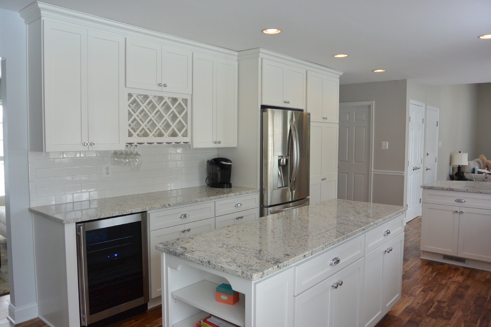 Eat-in kitchen - mid-sized transitional u-shaped medium tone wood floor and brown floor eat-in kitchen idea in Baltimore with an undermount sink, recessed-panel cabinets, white cabinets, granite countertops, white backsplash, subway tile backsplash, stainless steel appliances and an island