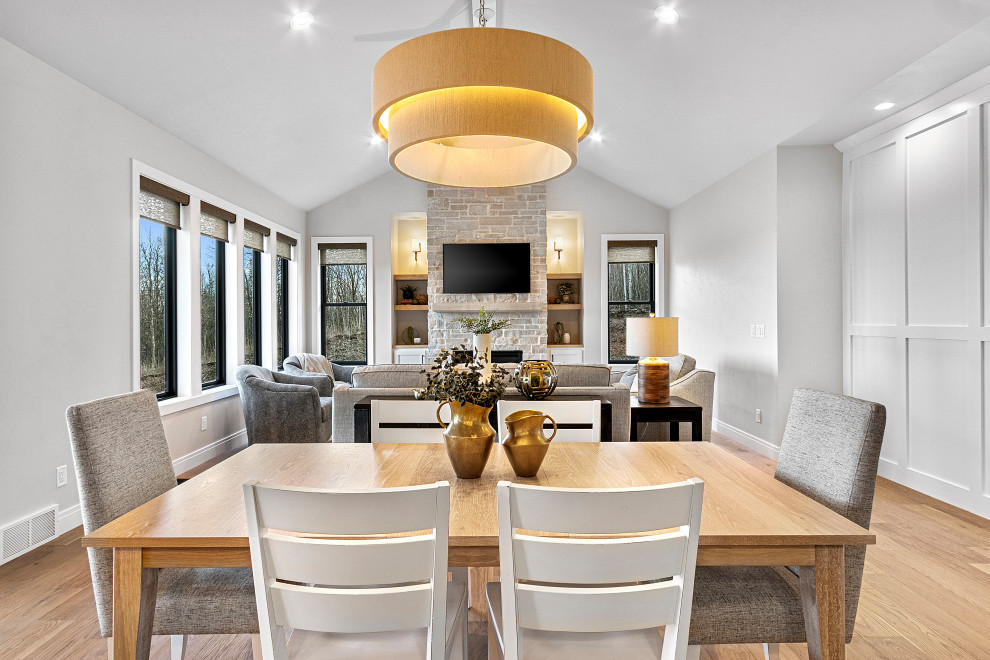 Kitchen/dining room combo - mid-sized transitional medium tone wood floor, brown floor and vaulted ceiling kitchen/dining room combo idea with white walls, a standard fireplace and a stone fireplace