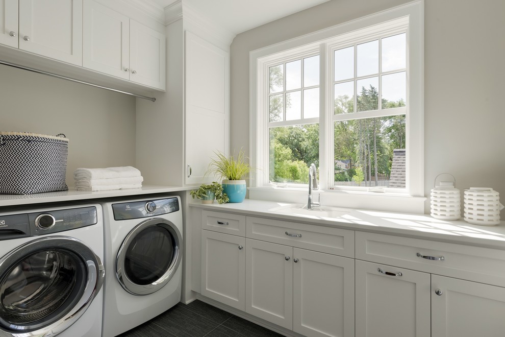 Inspiration for a mid-sized beach style dedicated laundry room in Minneapolis with an undermount sink, shaker cabinets, white cabinets, a side-by-side washer and dryer, grey floor, white benchtop, grey walls, quartz benchtops and ceramic floors.