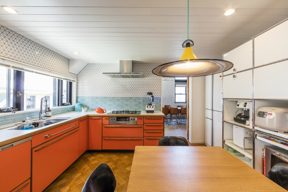 Beach style l-shaped open plan kitchen in Tokyo Suburbs with an undermount sink, flat-panel cabinets, orange cabinets, stainless steel appliances, medium hardwood floors, no island and brown floor.