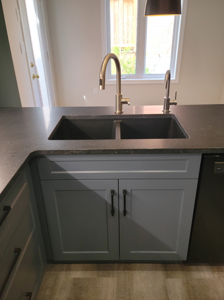 Example of a mid-sized transitional u-shaped vinyl floor eat-in kitchen design with an undermount sink, recessed-panel cabinets, blue cabinets, quartzite countertops, white backsplash, porcelain backsplash, black appliances, a peninsula and black countertops
