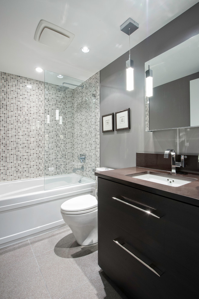Small contemporary bathroom in Vancouver with mosaic tile, an undermount sink, flat-panel cabinets, dark wood cabinets, engineered quartz benchtops, an alcove tub, a shower/bathtub combo, a one-piece toilet, gray tile, grey walls and ceramic floors.