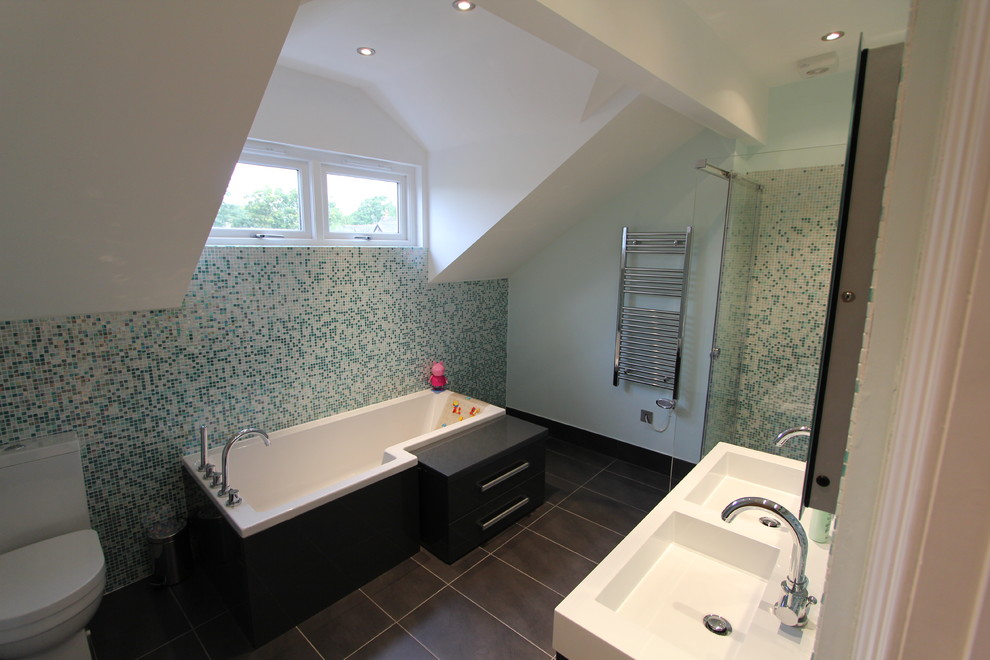 This is an example of a contemporary bathroom in Cheshire with an integrated sink, flat-panel cabinets, black cabinets, a freestanding tub, an alcove shower, a two-piece toilet, multi-coloured tile and mosaic tile.