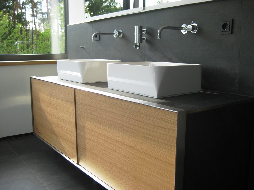 Modernes Badezimmer mit hellbraunen Holzschränken und gefliestem Waschtisch in Nürnberg