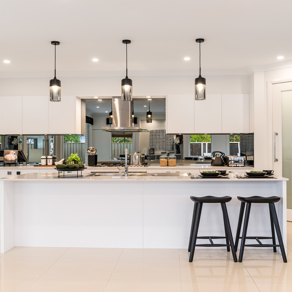 Large contemporary galley open plan kitchen in Other with a double-bowl sink, shaker cabinets, white cabinets, metallic splashback, mirror splashback, stainless steel appliances, ceramic floors, with island, beige floor and white benchtop.