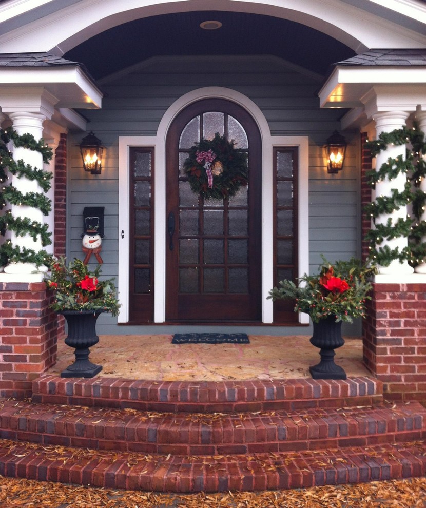 Design ideas for a mid-sized traditional front yard verandah in Charlotte with brick pavers.