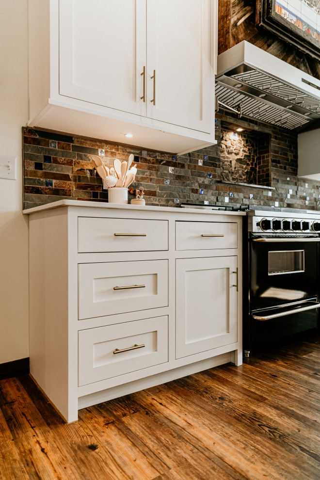 This is an example of a large country u-shaped eat-in kitchen in Other with an undermount sink, shaker cabinets, white cabinets, quartzite benchtops, brown splashback, stone tile splashback, panelled appliances, light hardwood floors, multiple islands, brown floor and white benchtop.