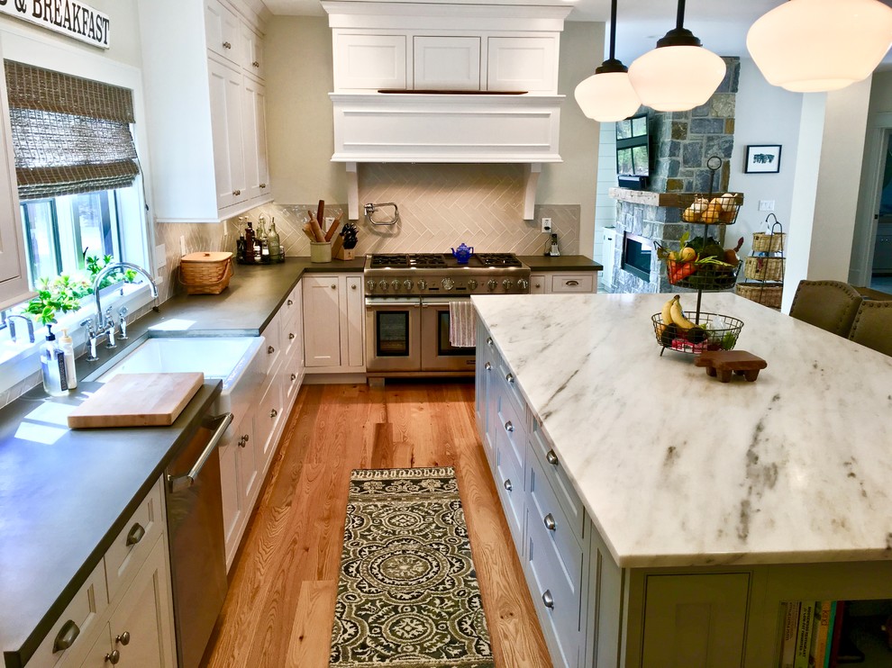Kitchen - transitional light wood floor and brown floor kitchen idea in New York with a farmhouse sink, white cabinets, concrete countertops, white backsplash, porcelain backsplash and stainless steel appliances