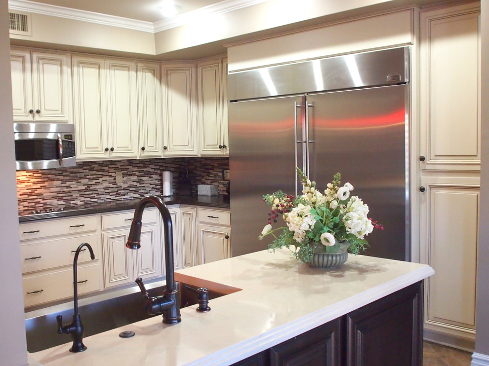 Example of a large transitional vinyl floor and brown floor open concept kitchen design in Phoenix with a farmhouse sink, raised-panel cabinets, white cabinets, solid surface countertops, brown backsplash, matchstick tile backsplash, stainless steel appliances and an island