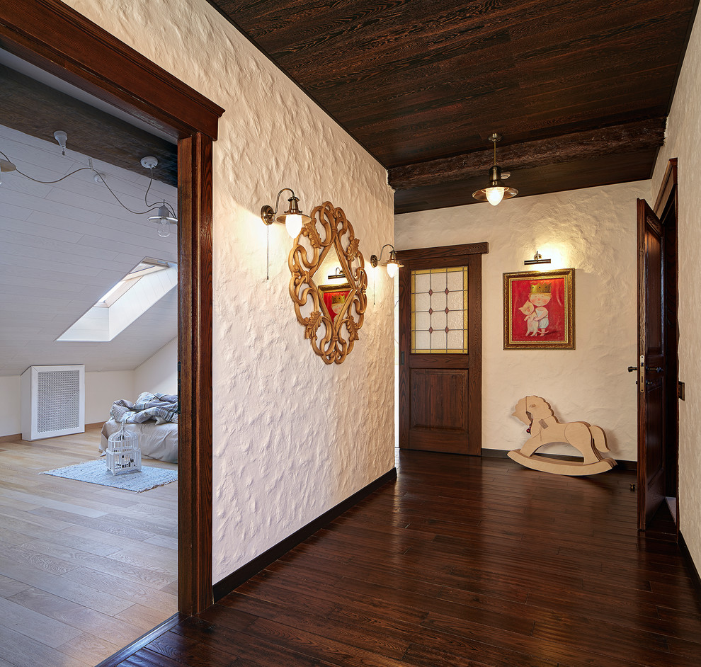 This is an example of a mid-sized country hallway in Yekaterinburg with white walls and dark hardwood floors.