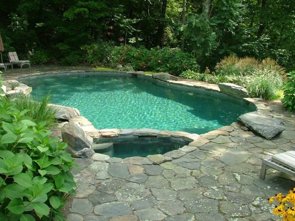Inspiration for a mid-sized country backyard custom-shaped natural pool in New York with natural stone pavers.