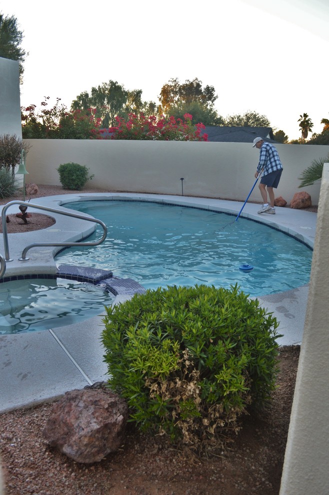 Modelo de piscina con fuente tradicional de tamaño medio a medida en patio trasero con adoquines de piedra natural